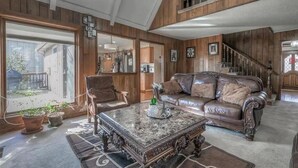 Ein geräumiges Wohnzimmer mit einer Ledersofa, einem Marmortisch und einer Treppe, die zu einer oberen Ebene führt.