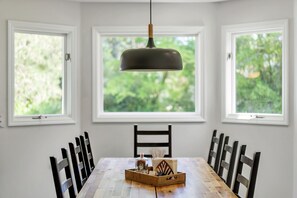 A dining area with a wooden table, black chairs, and a pendant light. - Spacious:  swimming pool, walk to the village. (Pinehurst)