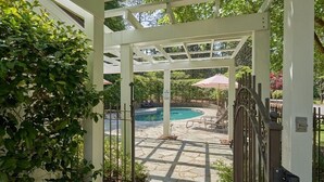 Un espace extérieur abrité comprenant une piscine, un revêtement de sol en pierre et une structure en forme de pergola.
