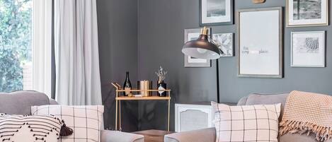 A modern living room with a grey wall, a wooden coffee table, a sofa, and a decorative lamp.