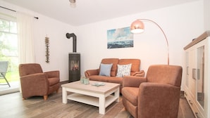 A living room with a sofa, two armchairs, a coffee table, a fireplace, and a lamp.