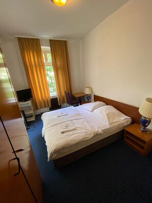 Una habitación de hotel con cama, escritorio con lámpara y televisor.