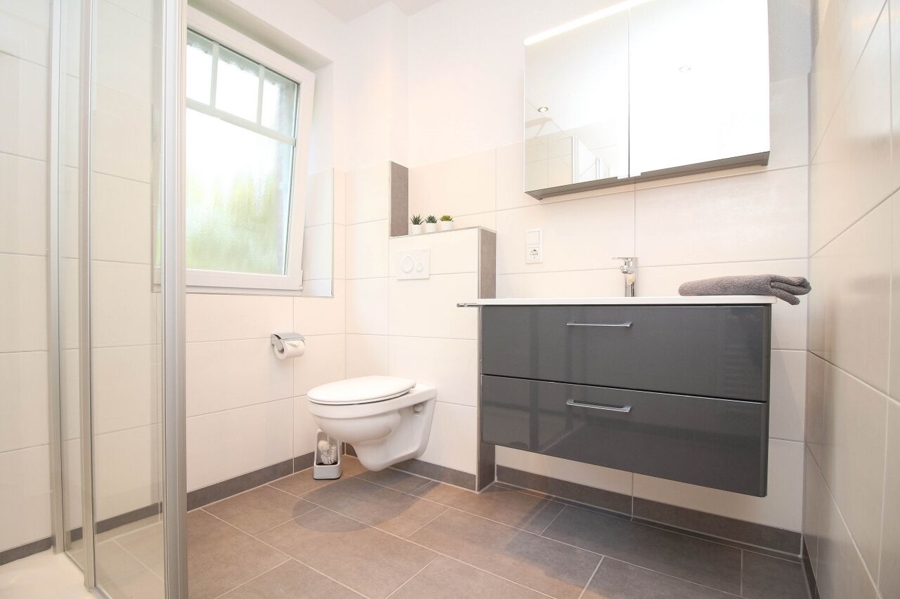 Ein modernes Badezimmer mit Toilette, Waschbecken und Schrank.