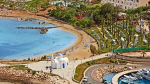 Un resort costero con villas frente a la playa, piscina y una pequeña iglesia.