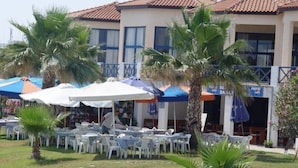 Un hotel con terraza al aire libre, palmeras y techo de tejas.