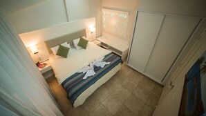 Una habitación de hotel con cama, mesitas de noche, ventana con proyección y armario.