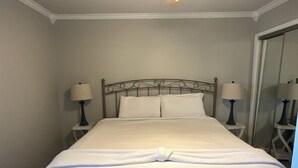 A neatly made bed in a hotel room with a metal headboard, two bedside tables with lamps, and a mirror on the wall. - 9A, Resting Beach Face (Destin)