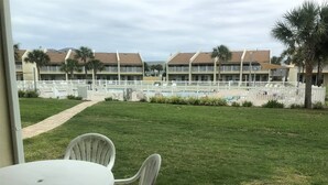 A view of a hotel courtyard with a white fence, a pool, and a building with multiple balconies. - 9A, Resting Beach Face (Destin)