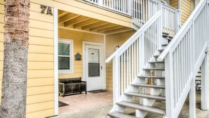 A two-story house with a white staircase, a front door, and a bench outside. - 7A, Sun Sand & Solitude (Destin)
