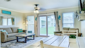 A living room with a sofa, coffee table, and chairs. There is a sliding glass door leading to a balcony. - 7A, Sun Sand & Solitude (Destin)