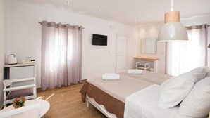 A modern bedroom with a bed, bedside table, and a television on the wall. - Marina Blue Studios (Mykonos)