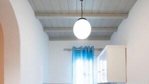 A compact kitchen with a refrigerator, sink, and a dining table with orange placemats. - Marina Blue Studios (Mykonos)