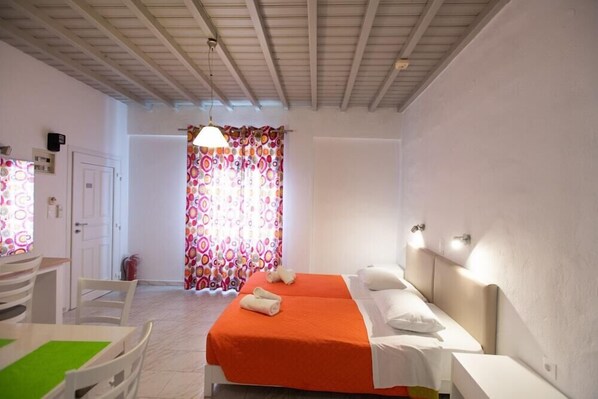 Une chambre d’hôtel avec un lit, un bureau et une chaise, ainsi qu’une fenêtre avec des rideaux.