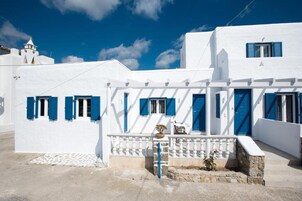 Un edificio blanco con contraventanas azules y base de piedra.