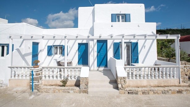 A white building with blue doors and shutters, stone steps, and a white railing. - Marina Blue Studios (Mykonos)