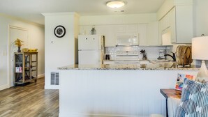 Een moderne keuken met witte kastjes, een inbouwmagnetron en een centraal eiland.