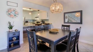 A dining area with a dark wooden table, six chairs, and a hanging light fixture.