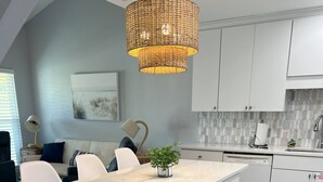 A modern kitchen with a central island, white cabinetry, and a hanging light fixture. - 8F, Isle Be Back (Destin)