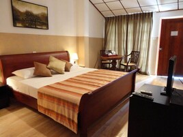 Una habitación de hotel con cama, escritorio, silla, televisión y un cuadro en la pared.