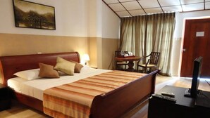 A hotel room with a bed, a desk, a chair, a television, and a painting on the wall. - Taprospa Tissa (Weerawila)