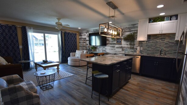 A modern kitchen with a central island, dark cabinets, and a stone backsplash. - 8B, Beach Please (Destin)