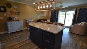 A kitchen with a central island, dark cabinets, and a coffee station. - 8B, Beach Please (Destin)