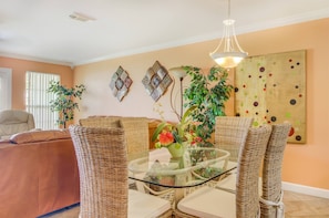 A living room with a glass coffee table, wicker chairs, a sofa, and decorative wall art.