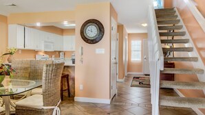 A kitchen with white cabinets, a microwave, and a dining area with wicker chairs and a glass table. - 4A, Castaway Cove (Destin)