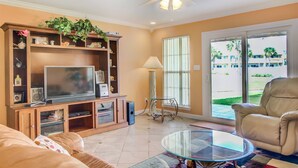 A living room with a television, shelves, a glass coffee table, a sofa, and a chair. - 4A, Castaway Cove (Destin)