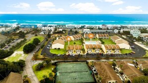 A coastal hotel with multiple buildings, a tennis court, and a parking area. - 7E, Shell We Stay? (Destin)
