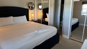 Une chambre à coucher bien rangée, avec un grand lit, des lampes de chevet, un ventilateur de plafond et un miroir au mur.