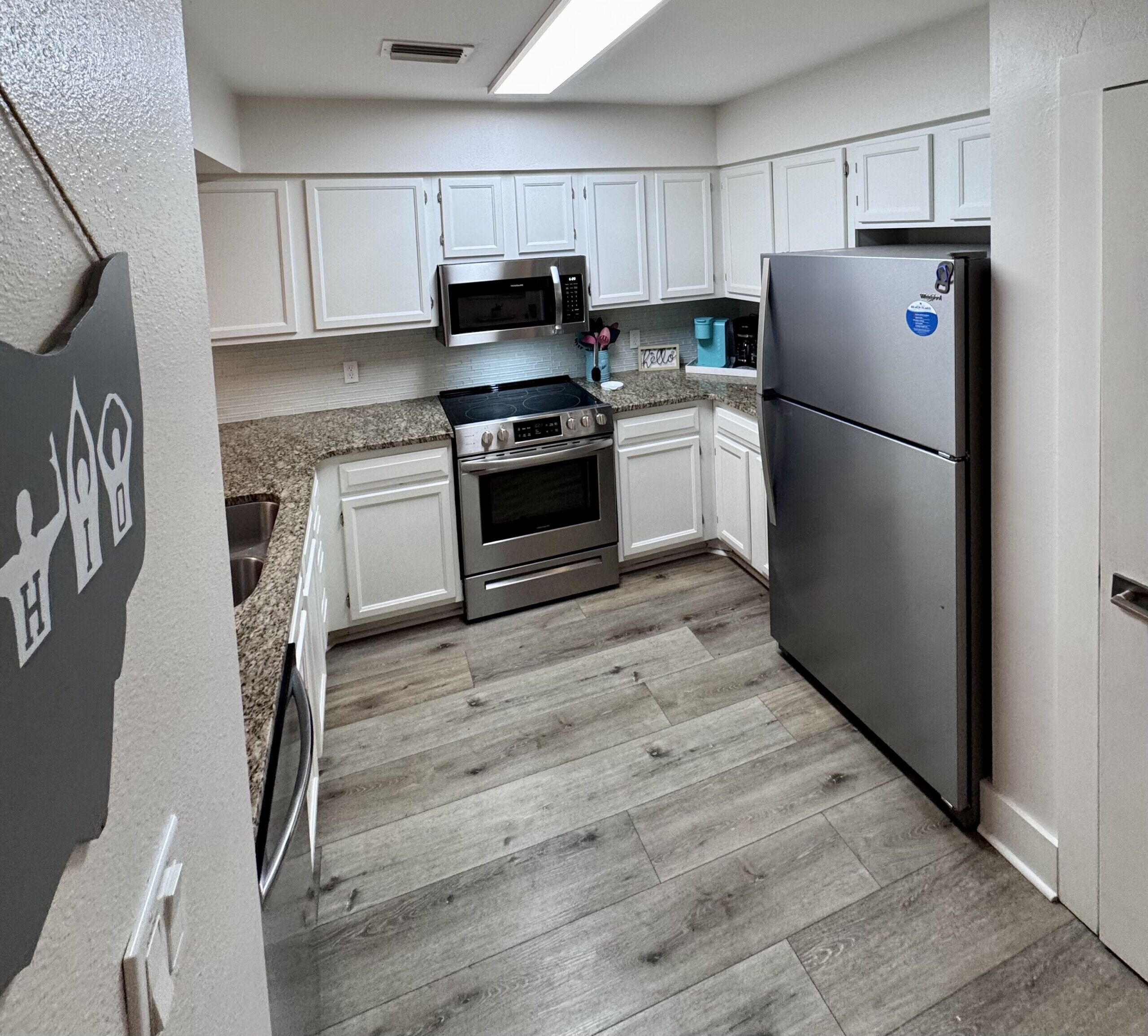A kitchen with white cabinets, a stainless steel refrigerator, a microwave, and an oven.