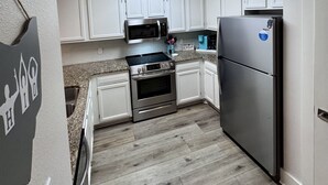 A kitchen with white cabinets, a stainless steel refrigerator, a microwave, and an oven.