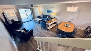 A spacious living area with a wooden floor, a dining table, and a sofa.