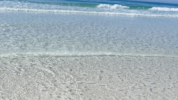A beach with clear water and gentle waves.