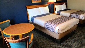 A hotel room with two beds, a round wooden table, and two chairs. - Capt. John Smith Inn (Williamsburg)