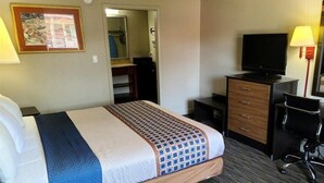 A hotel room with a bed, a desk, a chair, a television, and a mirror. - Capt. John Smith Inn (Williamsburg)