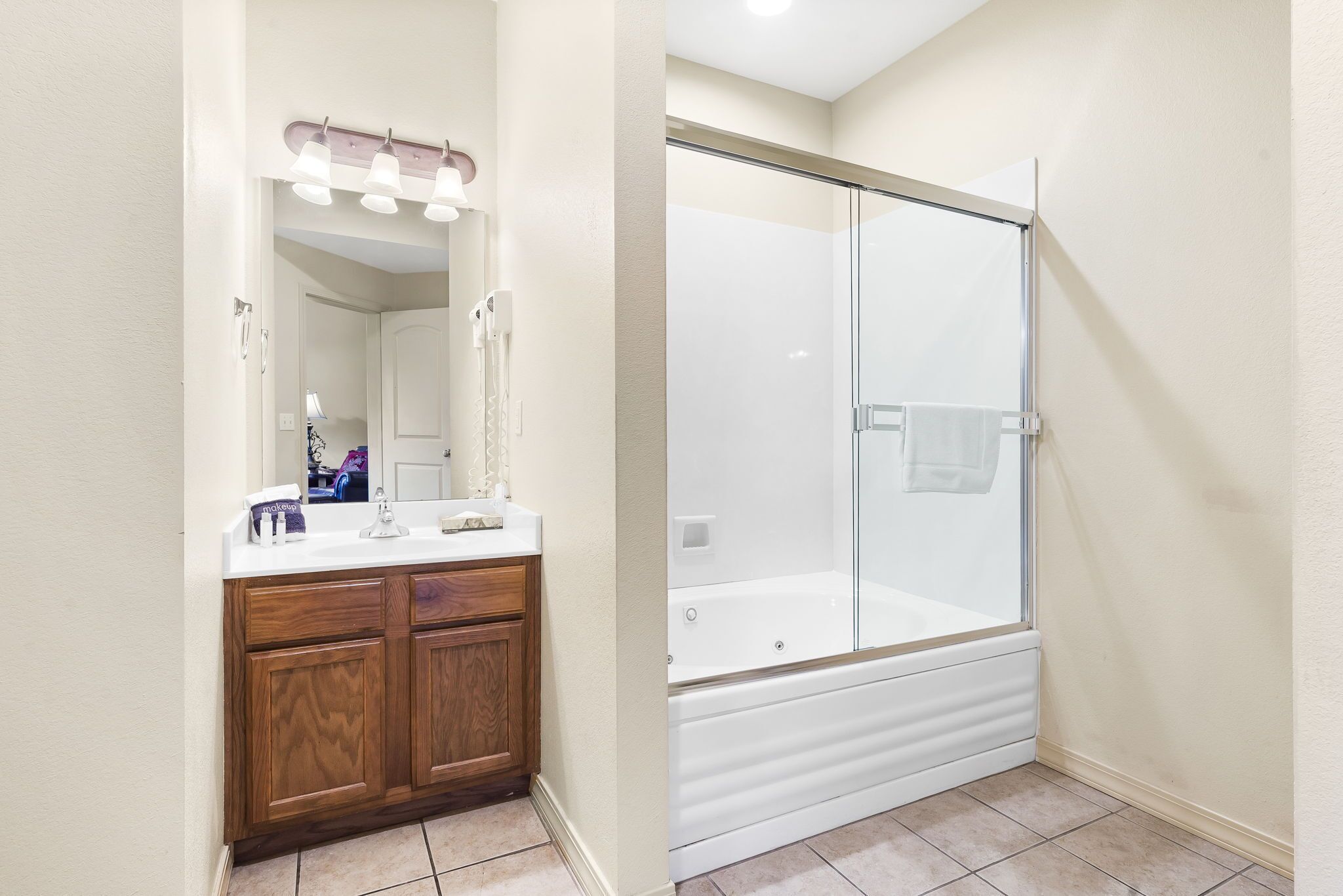 Une salle de bain avec un meuble-lavabo en bois, un grand miroir et une douche à l’italienne.