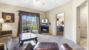 A living room with a fireplace, a television, and a view of the outdoors. - King Bedroom, 1 Bathroom + Adjoining Queen Suite Golf Condo (Branson)