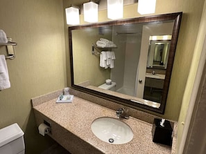 A bathroom with a granite countertop, a sink, a mirror, and a towel rack. - Williamsburg Historic District (Williamsburg)