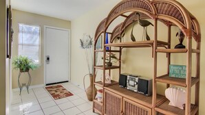A room with a wicker console table, a white door, a tiled floor, and a small plant by the door. - 3A, Rumrunner Retreat (Destin)