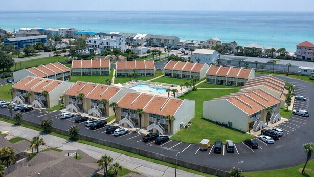 A coastal hotel with multiple buildings, a swimming pool, and a parking lot. - 3A, Rumrunner Retreat (Destin)
