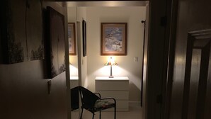 A dimly lit hallway with a chair and a table with a lamp. There are framed pictures on the walls. - Fantasy Island Inn - Poolside Queen Room 3 (Wilton Manors)