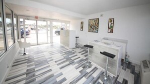Un vestíbul modern amb un paviment estampat, una recepció i una porta de vidre que dona a l'exterior.