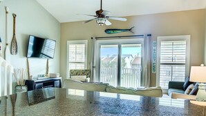 A kitchen with a granite countertop, a ceiling fan, a television mounted on the wall, and a fish decoration. - 9H, Rhythm & Waves Retreat (Destin)