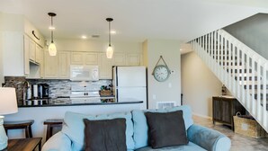 A modern kitchen with white cabinets, a central island, and pendant lighting. - 9H, Rhythm & Waves Retreat (Destin)