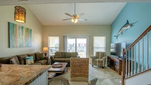 A spacious living area with a large window, a ceiling fan, and a television. - 9G, Tan Lines & Good Times (Destin)