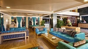 A spacious lobby with multiple seating areas, a reception desk, and a visible staircase. - Club Felicia Village (Manavgat)