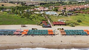 An aerial view of a coastal resort with a beach, tennis courts, and a pool area. - Club Felicia Village (Manavgat)