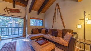 Una sala de estar acogedora con un sofá modular, suelo de madera y un amplio ventanal con vistas al exterior.